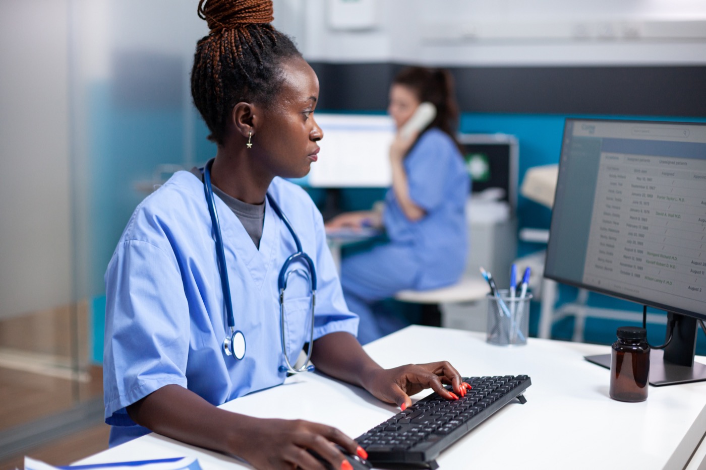 Ugandan nurse with tablet showing patient digital records in a hospital ward
