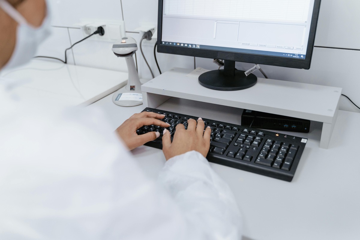 Ugandan male doctor reviewing patient records on a desktop computer